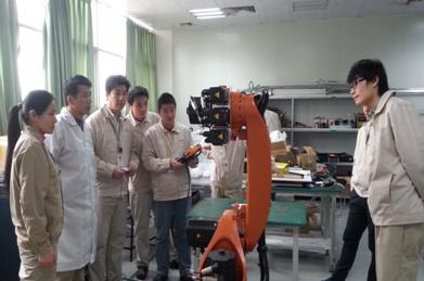 （圖一）我校專業(yè)教師與企業(yè)技術骨干共同學習機器人的操作