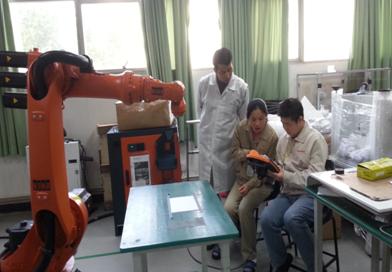 （圖一）我校專業(yè)教師與企業(yè)技術骨干共同學習機器人的操作